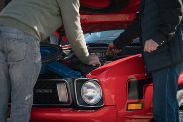 Concept of two men repairing the v8 engine of the old classic American first generation pony car....