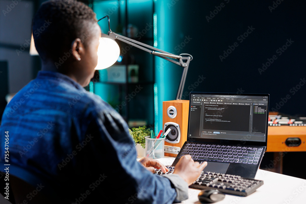 Poster focused african american woman managing software and programming code on laptop. skilled female prog