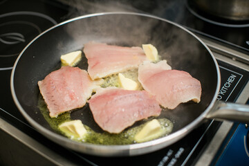 fish fillets cooking with butter in pan