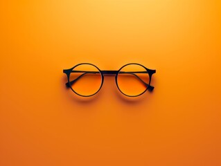 Sleek round black eyeglasses cast a subtle shadow on a bright orange backdrop, a classic accessory with a modern twist.