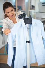 smiling woman ironing shirt at home