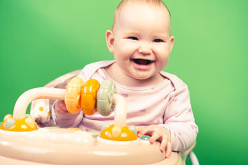 Baby Sitting in High Chair on Green Background. The baby is sitting in a walker