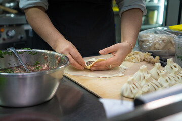 Close-up of female chef's hands sculpting khinkali. Process of cooking khinkali in the kitchen in the restaurant
