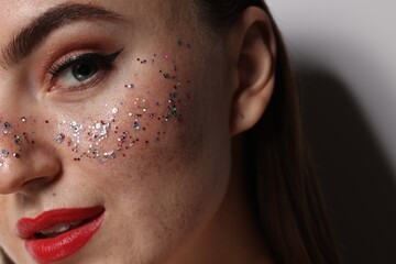 Beautiful woman with glitter freckles on grey background, closeup