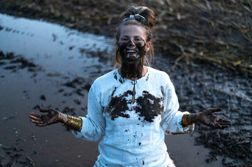 A happy authentic woman stuck in a mud puddle in a field