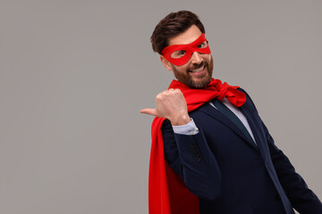 Happy businessman wearing red superhero cape and mask on beige background