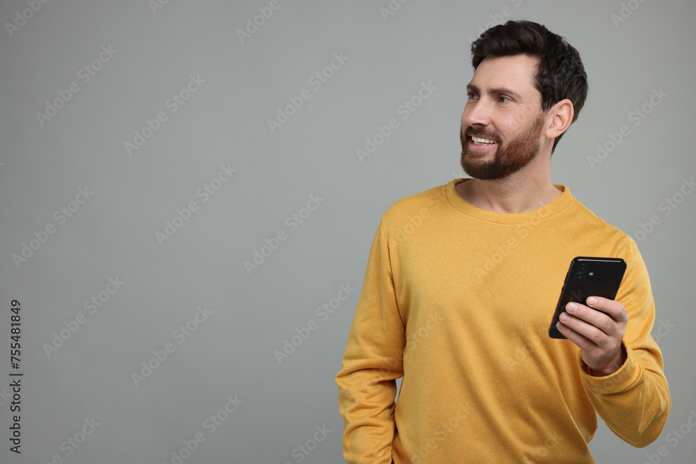 Poster smiling man with smartphone on grey background. space for text