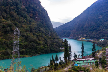 Teesta River with its sparkling green water is flowing through a valley surrounded by lush green mountains. Sikkim, India