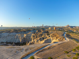 Colorful balloons fly over the valley of fabulous chimneys in Nevsehir, Goreme, Cappadocia, Turkey. Breathtaking panoramic view from a drone in Cappadocia, hot air balloon tourism.