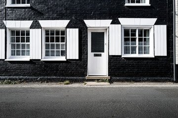 Large, black painted terraced seaside holiday home in the Suffolk coastal town of Southwold. Double yellow lines can be seen in front of the house, located down a narrow street.