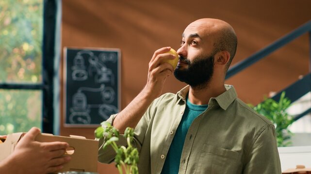 Storekeeper gives fresh lemons to man to smell and enjoy organic natural citrus scent, buying locally grown fruits from grocery store vendor. Adult supporting local small business. Handheld shot.
