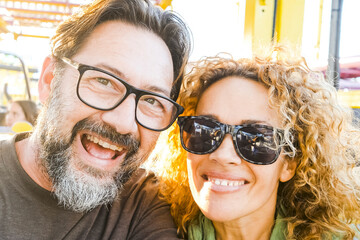 Happy smiling young couple at theme park smile enjoying rides at amusement park. Close-up of happy fifty year old couple at theme amusement park. travel, tourism, couple, people, vacation concept