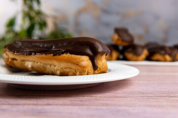 French ecler with chocolate on white plate. Traditional french dessert eclair.