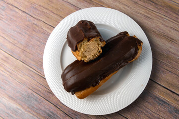 French ecler with chocolate on white plate. Traditional french dessert eclair.