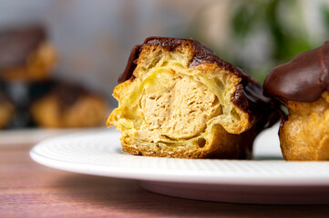 French ecler with chocolate on white plate. Traditional french dessert eclair.