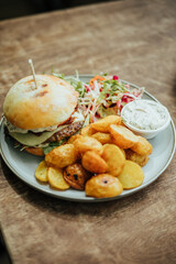 beef burger with roasted potatoes on wood table summer cafe
