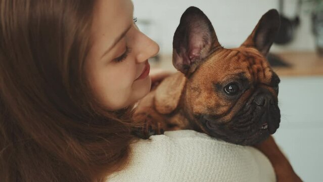 Young woman gently holds her French Bulldog, their faces close together in moment of peaceful companionship. Intimacy and trust, deep connection pets forge with their humans