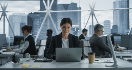 Lay Offs, Reductions and Stress Concept: Female Project Manager working On Laptop In Skyscraper...
