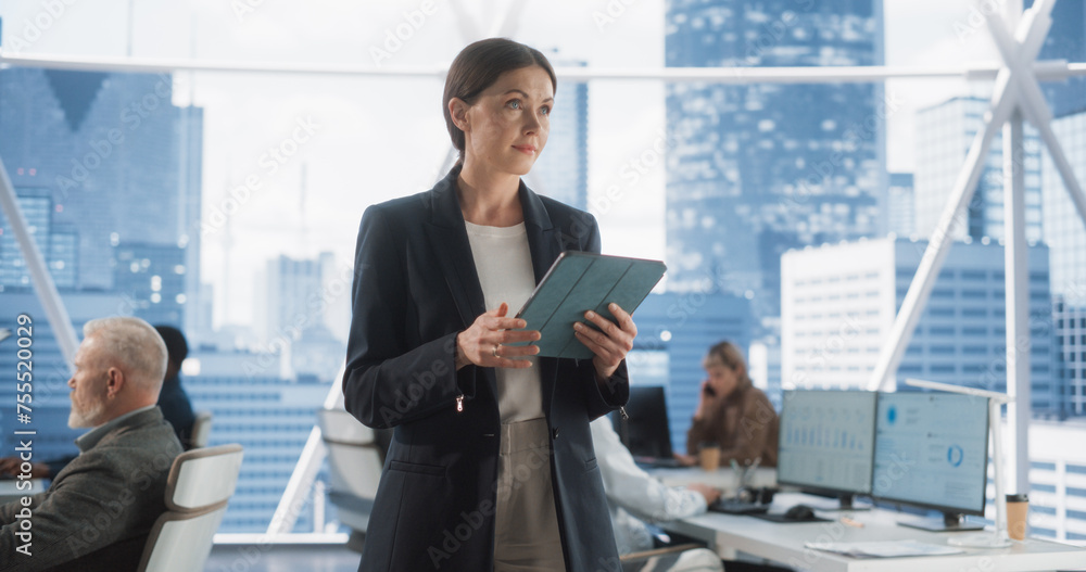 Poster successful businesswoman using tablet computer, standing in modern diverse office in downtown and wo