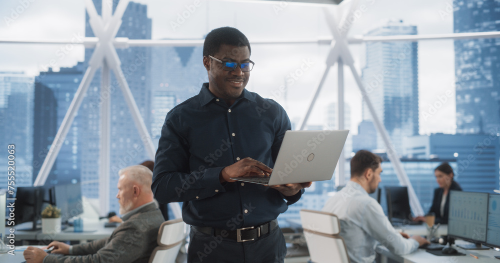 Poster Handsome African American CEO Walking In Modern Skyscraper Office With Diverse Employees In Downtown. Succeful Black Man Using Laptop Computer To Go Through Tasks And Business Meetings In Tech Startup