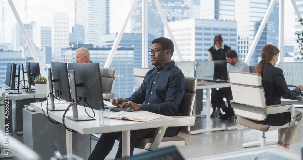 Poster Focused African American Male Data Analyst Typing On Desktop Computer In Diverse Corporate Office With Megapolis Window View. Professional Balck Man Working In Consulting Company With Colleagues.