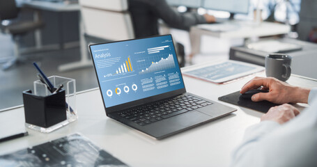 Close Up On Hands of Caucasian Male Professional Working in a Business Research and Development Company. Manager Analyzing Financial Reports, Looking at a Laptop Computer Screen with Graphs and Charts