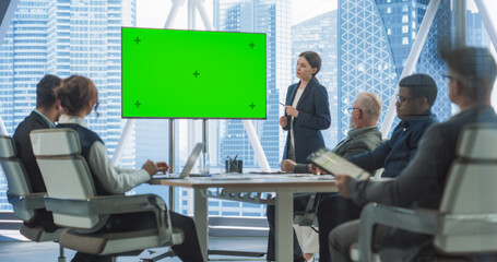 Office Conference Room Presentation: Beautiful Businesswoman Talks, Uses Green Screen Chroma Key TV Set. Digital Entrepreneur Presents e-Commerce Product On Meeting With Group Diverse Investors.