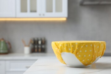 Bowl covered with beeswax food wrap on white table indoors, space for text