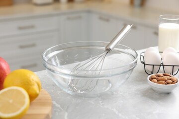 Fototapeta na wymiar Metal whisk, bowl and different products on gray marble table in kitchen