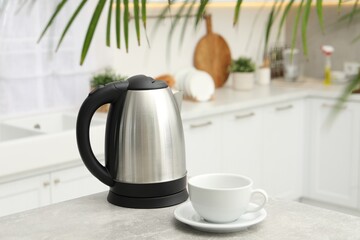 Electric kettle and cup on table in kitchen. Space for text