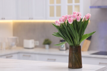 Beautiful bouquet of fresh pink tulips on table in kitchen. Space for text