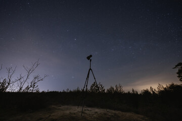 Landscape astrophotography, camera on a tripod against the backdrop of the starry sky in nature.
