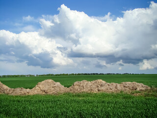 The beginning of spring in the countryside. A field seeded with wheat. An old stack of straw.