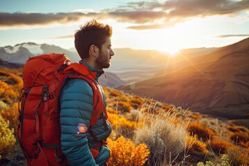 A man wearing an orange backpack is standing on a hillside with a beautiful suns