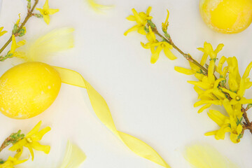 Wielkanoc w żółtych barwach, wiosenna żółta forsycja, pisanki, piórka i wstążki. 
