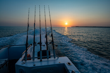 Sunrise behind a fishing boat with fishing rods