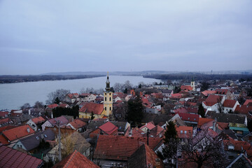 Panoramic view of historic old town Zemun, part of Belgrade, Serbia. Beautiful view of the Danube river, the tiled red roofs of the houses and the clock tower of the church at sunset.