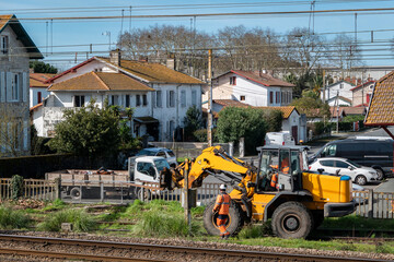 Trabalhadores realizando manutenção nas linhas de comboio com máquina de carregamento frontal em meio a uma área urbana