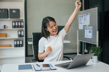 Overjoyed charming excited asian business woman worker using laptop working in office, feeling happy.