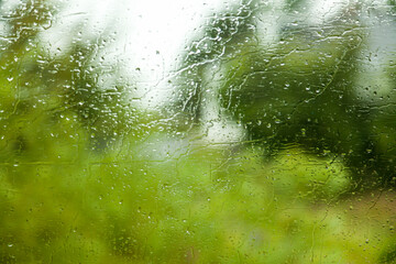 ventana con gotas de agua y vao por la lluvia en el exterior visualizando un paisaje de arboles verdes a través de las costas