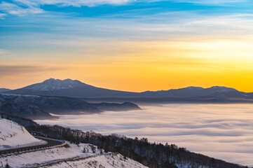 朝の峰から見るシルクのような雲と山々のシルエットと美しいグラデーションの空。