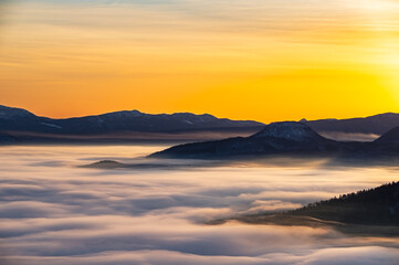 Fototapeta na wymiar 朝の峰から見るシルクのような雲と山々のシルエット。