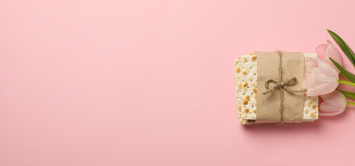 Matzo and flowers on pink background, space for text