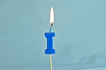 close up on a blue letter A birthday candle with fire on a white background.
