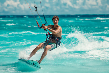 Attractive young man kitesurfing in the sea - obrazy, fototapety, plakaty