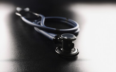 Dark blue stethoscope lying on black background closeup. Medical education concept