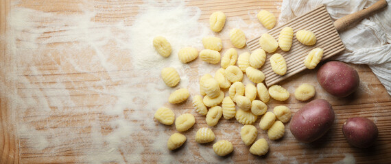 Potato gnocchi with durum wheat flour and gnocchi board on wooden pastry board, top view, space for text, close-up. - 755556825