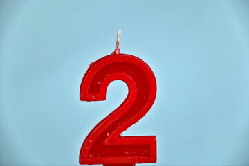 close up on red number second birthday candle on a white background.
