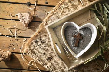Heart-shaped container with ashes and wooden cross top view