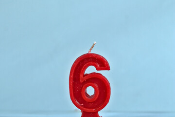 close up on red number sixth birthday candle on a white background.
